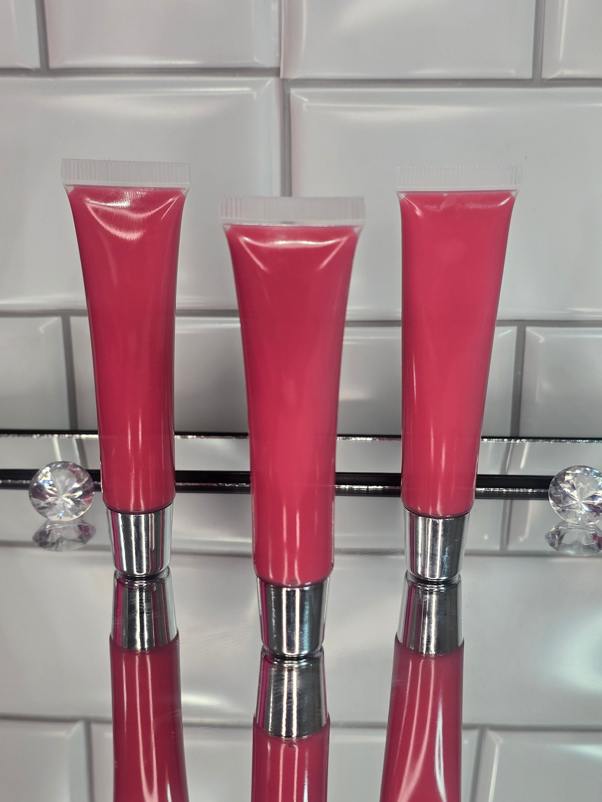 Blush hot pink lip gloss tubes on a mirror surface